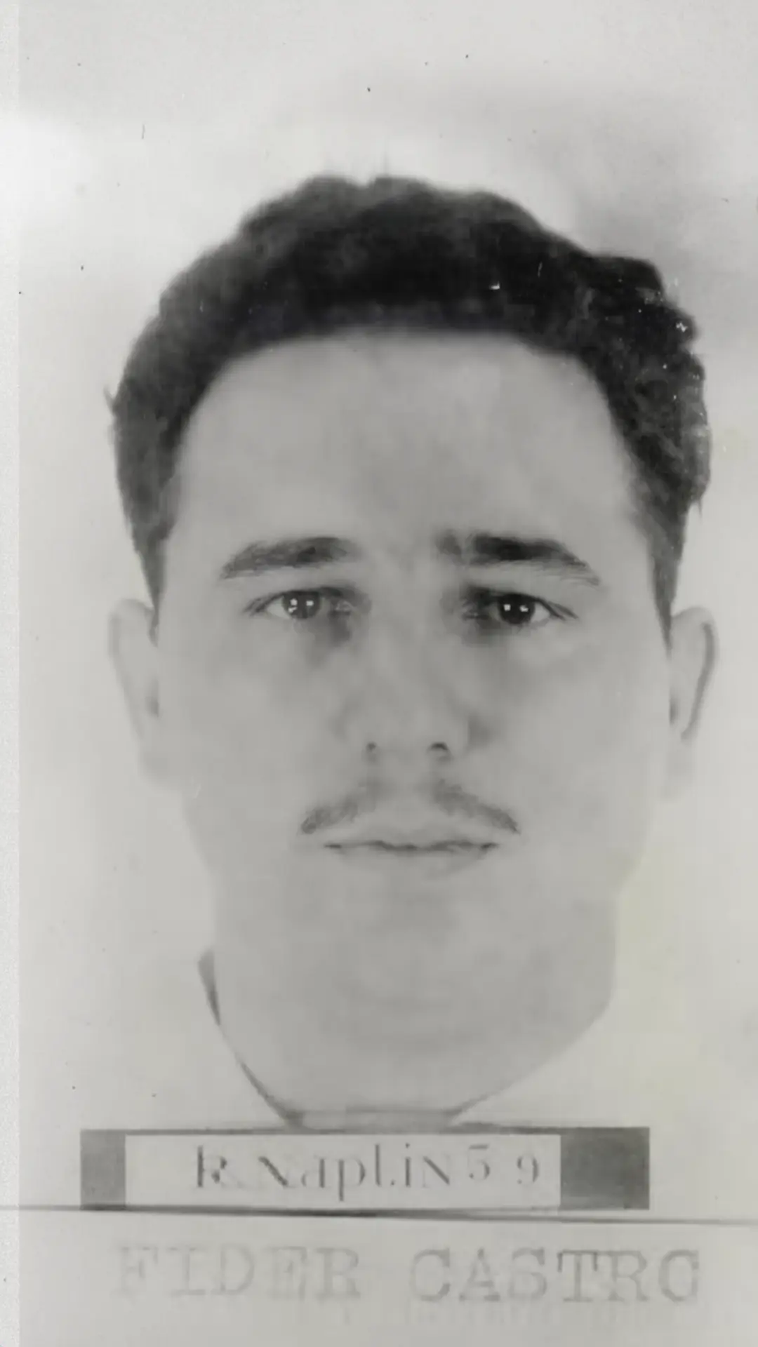 Black-and-white identification photograph of a young man with a moustache holding a name placard
