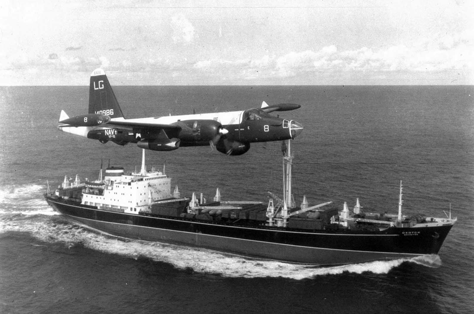 A U.S. Navy patrol aircraft flying low over a Soviet cargo ship at sea