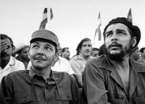 Small black-and-white photograph of two uniformed men, one in a cap and one in a beret, looking up above a crowd